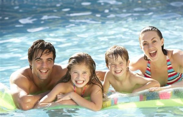 Young Family Relaxing In Swimming Pool
